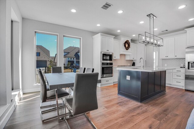 18702 Denio Site Dr, Cypress, TX 77433 - kitchen featuring stainless steel appliances, light countertops, tasteful backsplash, white cabinetry, and recessed lighting