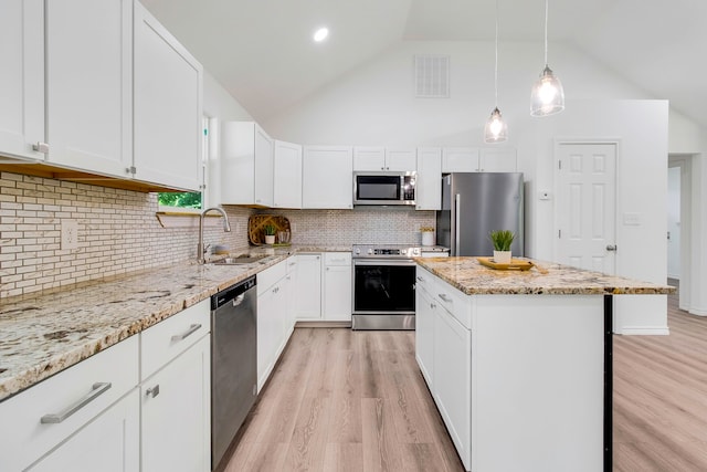 220 Tortuga Way, Point Blank, TX 77364 - kitchen featuring appliances with stainless steel finishes, light wood-style floors, a center island, white cabinetry, and light stone counters