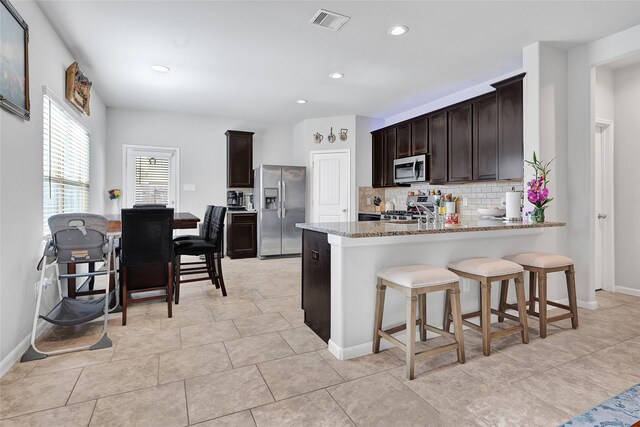 1410 Woods Lake Ct, Houston, TX 77047 - kitchen featuring appliances with stainless steel finishes, light stone counters, backsplash, dark brown cabinetry, and recessed lighting