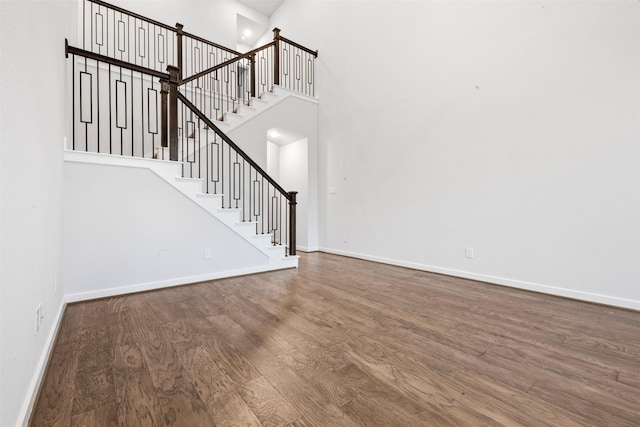 19911 Curved Steel Dr, Cypress, TX 77433 - unfurnished living room featuring wood finished floors, a towering ceiling, and stairway