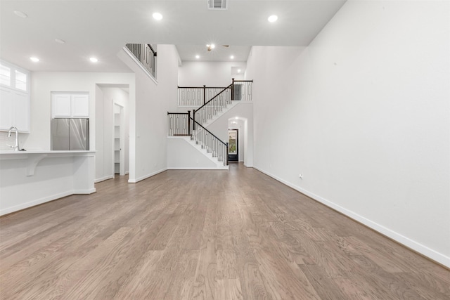 19911 Curved Steel Dr, Cypress, TX 77433 - unfurnished living room featuring light wood-style floors, recessed lighting, and stairs