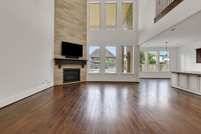 24918 Granite Bluff Ln, Katy, TX 77494 - unfurnished living room featuring dark wood-type flooring, a fireplace, and a high ceiling