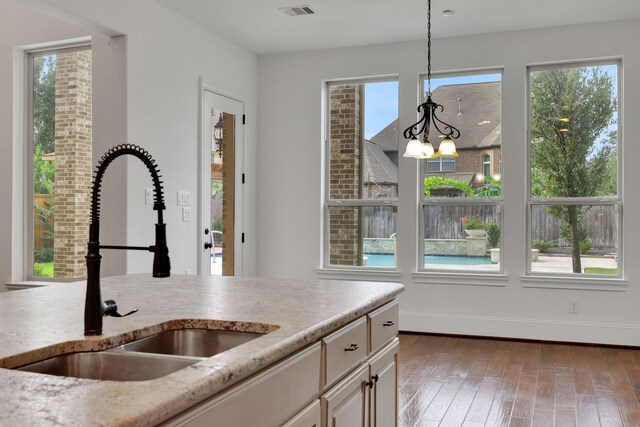 24918 Granite Bluff Ln, Katy, TX 77494 - kitchen with plenty of natural light, a chandelier, wood finished floors, and light stone counters