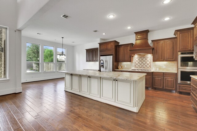 24918 Granite Bluff Ln, Katy, TX 77494 - kitchen featuring stainless steel appliances, premium range hood, an island with sink, backsplash, and light stone counters