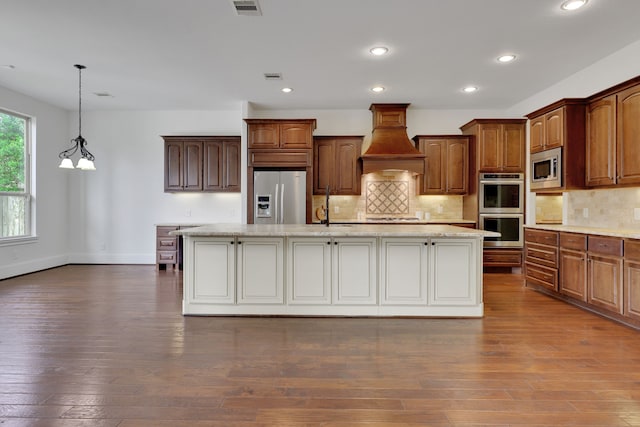 24918 Granite Bluff Ln, Katy, TX 77494 - kitchen featuring appliances with stainless steel finishes, custom exhaust hood, a spacious island, tasteful backsplash, and recessed lighting