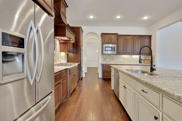 24918 Granite Bluff Ln, Katy, TX 77494 - kitchen with appliances with stainless steel finishes, arched walkways, custom exhaust hood, decorative backsplash, and light stone countertops