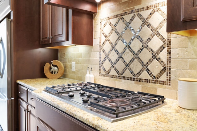 24918 Granite Bluff Ln, Katy, TX 77494 - kitchen featuring stainless steel gas stovetop, freestanding refrigerator, decorative backsplash, and light stone countertops
