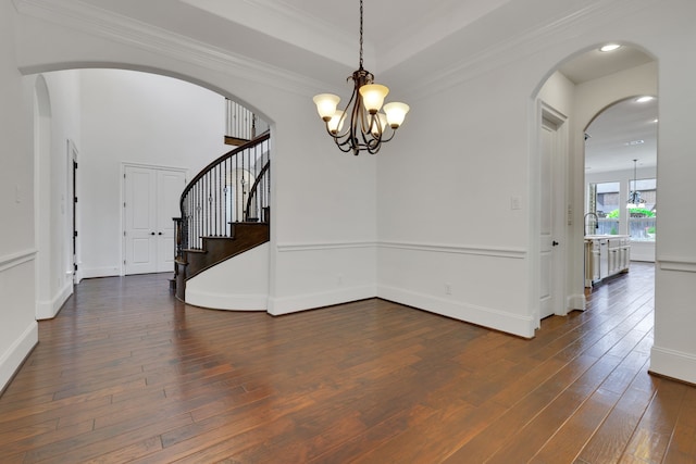 24918 Granite Bluff Ln, Katy, TX 77494 - unfurnished room featuring a chandelier, dark wood-style flooring, arched walkways, stairway, and crown molding