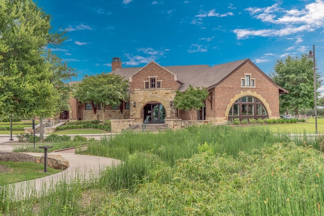 24918 Granite Bluff Ln, Katy, TX 77494 - tudor house with stone siding, a chimney, and brick siding