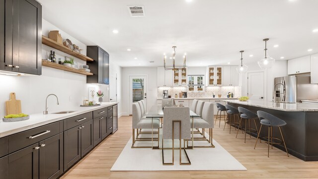 6414 Woodbrook Ln, Houston, TX 77008 - kitchen with stainless steel fridge, a kitchen breakfast bar, backsplash, open shelves, and light wood-type flooring