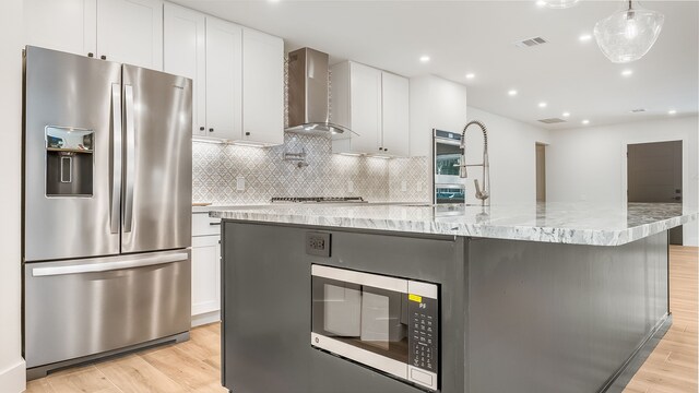 6414 Woodbrook Ln, Houston, TX 77008 - kitchen featuring stainless steel appliances, wall chimney range hood, light wood-type flooring, white cabinets, and recessed lighting