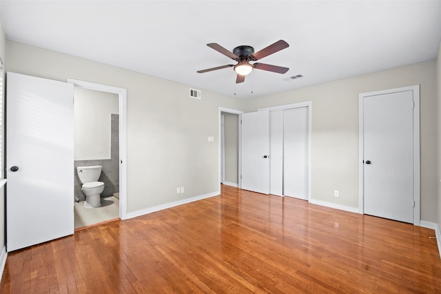 9614 Hammerly Blvd, Houston, TX 77080 - unfurnished bedroom featuring wood finished floors, multiple closets, connected bathroom, and a ceiling fan