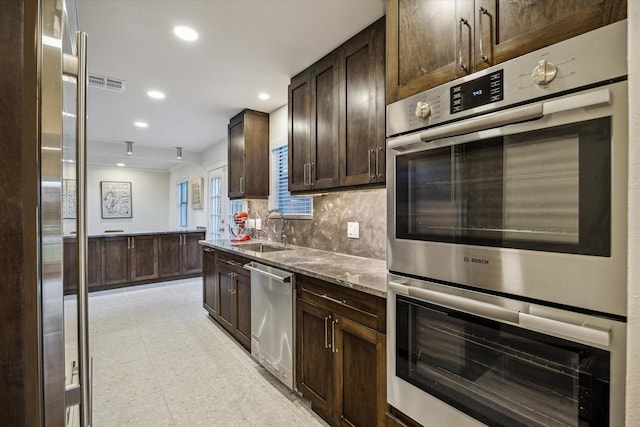 10707 Moonlight Dr, Houston, TX 77096 - kitchen with appliances with stainless steel finishes, dark brown cabinets, recessed lighting, tasteful backsplash, and stone counters