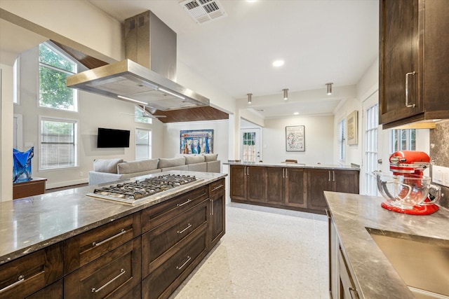 10707 Moonlight Dr, Houston, TX 77096 - kitchen with stainless steel gas cooktop, island exhaust hood, stone counters, dark brown cabinets, and open floor plan