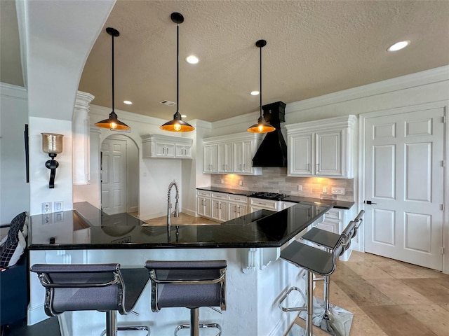 12571 St Ann Ct, Willis, TX 77318 - kitchen featuring a peninsula, backsplash, white cabinetry, premium range hood, and a textured ceiling