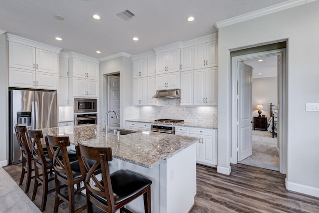 3207 Coach Horse Ln, Houston, TX 77080 - kitchen featuring appliances with stainless steel finishes, ornamental molding, under cabinet range hood, dark wood finished floors, and white cabinets