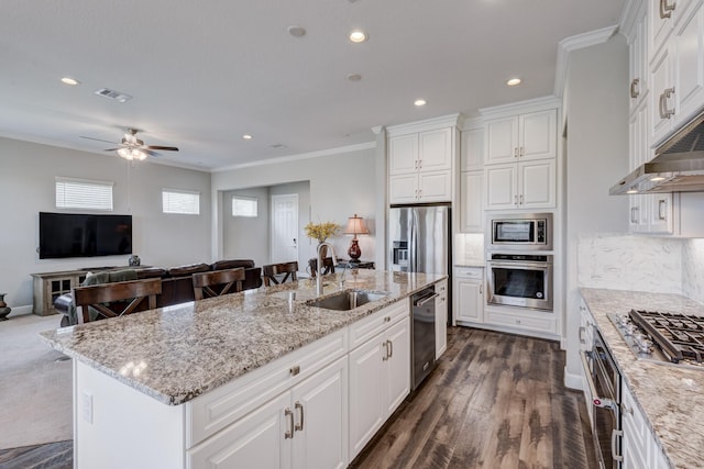3207 Coach Horse Ln, Houston, TX 77080 - kitchen featuring appliances with stainless steel finishes, open floor plan, ornamental molding, a center island with sink, and white cabinets