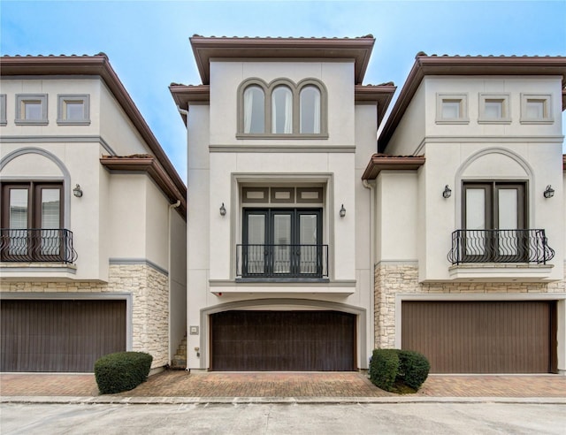 5531 Pine St Unit H, Houston, TX 77081 - view of front of property with a balcony, an attached garage, stucco siding, and stone siding