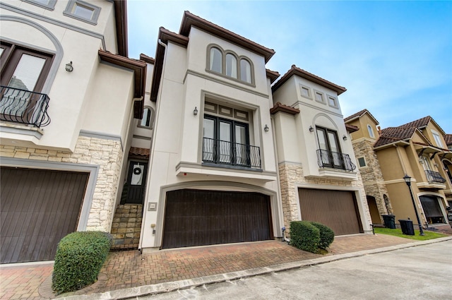 5531 Pine St Unit H, Houston, TX 77081 - view of front facade featuring stone siding, a balcony, stucco siding, an attached garage, and decorative driveway