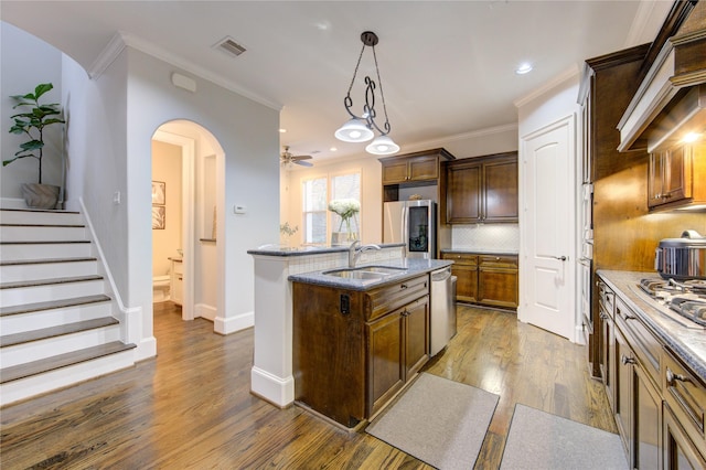 5531 Pine St Unit H, Houston, TX 77081 - kitchen featuring stainless steel appliances, an island with sink, custom exhaust hood, decorative backsplash, and dark wood-type flooring