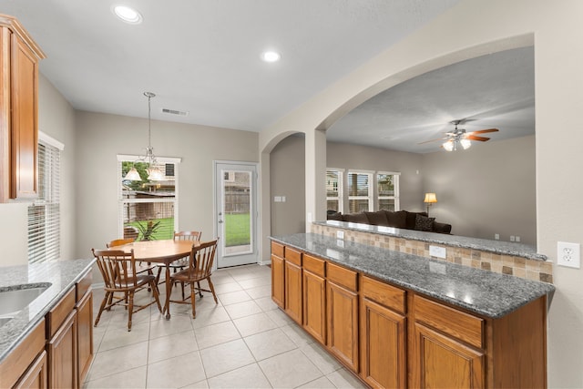 31820 Forest Oak Ln, Conroe, TX 77385 - kitchen with a ceiling fan, brown cabinetry, light tile patterned flooring, arched walkways, and recessed lighting