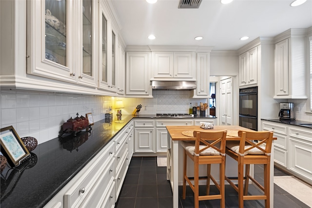 1311 Peden St, Houston, TX 77006 - kitchen featuring dark tile patterned floors, under cabinet range hood, white cabinetry, and recessed lighting