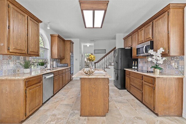 1711 Alcorn Bayou Dr, Sugar Land, TX 77479 - kitchen with black appliances, a kitchen island, tasteful backsplash, and light stone finish floors