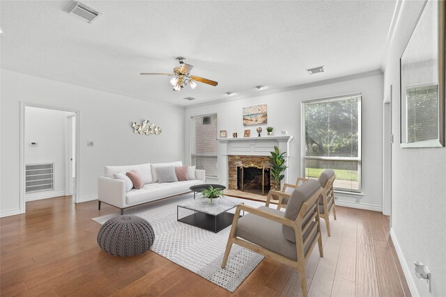 1711 Alcorn Bayou Dr, Sugar Land, TX 77479 - living room featuring a stone fireplace, a ceiling fan, a textured ceiling, wood finished floors, and crown molding