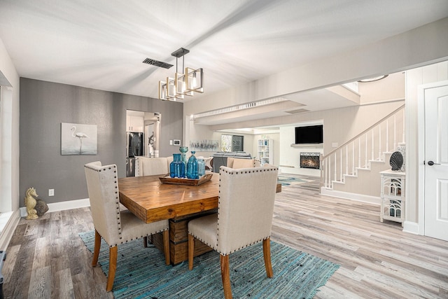 3611 18th St N, Texas City, TX 77590 - dining room with light wood-style flooring, stairs, a chandelier, and a lit fireplace