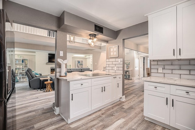 3611 18th St N, Texas City, TX 77590 - kitchen featuring light wood-style floors, black electric cooktop, open floor plan, white cabinetry, and light stone countertops