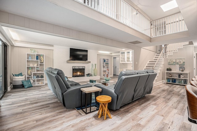 3611 18th St N, Texas City, TX 77590 - living area featuring stairs, wood finished floors, a towering ceiling, a brick fireplace, and a skylight