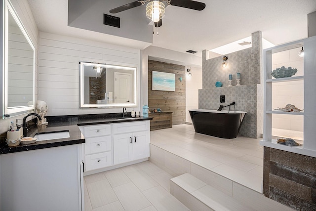 3611 18th St N, Texas City, TX 77590 - full bathroom featuring two vanities, a ceiling fan, a freestanding tub, wood walls, and walk in shower