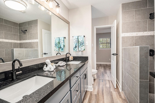 3611 18th St N, Texas City, TX 77590 - full bathroom with wood finished floors, double vanity, a tile shower, and a textured ceiling