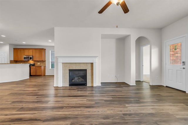3510 Orchard Valley Ln, Spring, TX 77386 - unfurnished living room featuring recessed lighting, arched walkways, healthy amount of natural light, a ceiling fan, and a fireplace