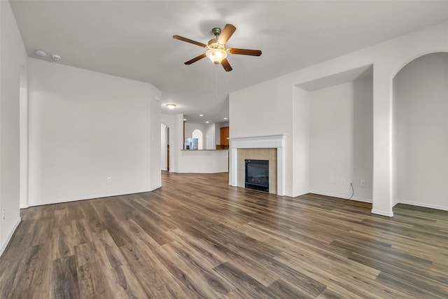 3510 Orchard Valley Ln, Spring, TX 77386 - unfurnished living room featuring a ceiling fan, dark wood-style floors, a fireplace, and arched walkways