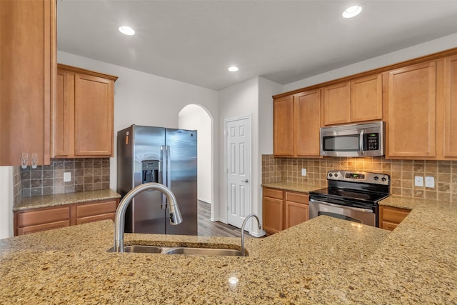 3510 Orchard Valley Ln, Spring, TX 77386 - kitchen featuring stainless steel appliances, arched walkways, light stone counters, tasteful backsplash, and recessed lighting