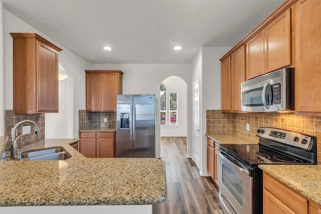 3510 Orchard Valley Ln, Spring, TX 77386 - kitchen featuring stainless steel appliances, arched walkways, light stone countertops, dark wood-style flooring, and backsplash