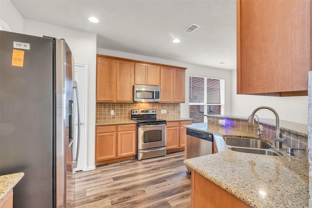 3510 Orchard Valley Ln, Spring, TX 77386 - kitchen with appliances with stainless steel finishes, light wood-type flooring, decorative backsplash, light stone countertops, and recessed lighting
