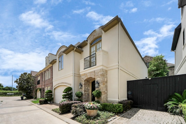 6310 Hermann Lake Dr, Houston, TX 77021 - view of side of property featuring a balcony, stone siding, a garage, a gate, and driveway