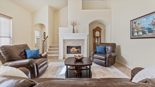 14822 Meridian Park Ln, Humble, TX 77396 - carpeted living room featuring arched walkways, tile patterned flooring, a tiled fireplace, and a high ceiling