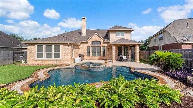 14822 Meridian Park Ln, Humble, TX 77396 - back of property with brick siding, a patio, a fenced backyard, a chimney, and a pool with connected hot tub