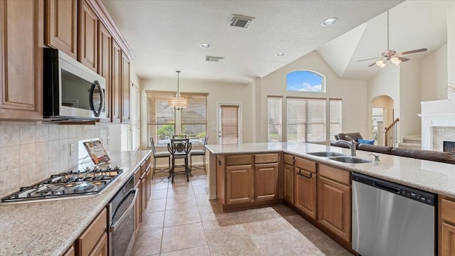 14822 Meridian Park Ln, Humble, TX 77396 - kitchen with stainless steel appliances, tasteful backsplash, a fireplace, a ceiling fan, and vaulted ceiling