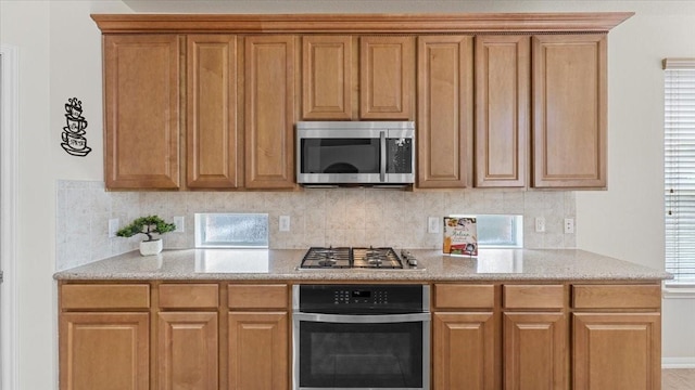 14822 Meridian Park Ln, Humble, TX 77396 - kitchen with appliances with stainless steel finishes, decorative backsplash, light stone countertops, and brown cabinetry