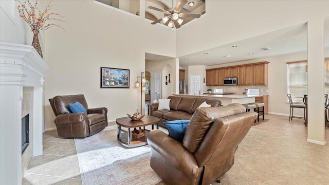 14822 Meridian Park Ln, Humble, TX 77396 - living room with light tile patterned floors, ceiling fan, a fireplace, and a towering ceiling