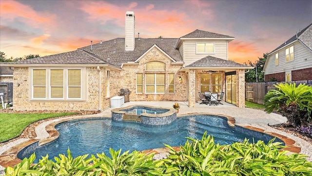 14822 Meridian Park Ln, Humble, TX 77396 - back of property at dusk featuring a patio area, a fenced backyard, brick siding, and a pool with connected hot tub