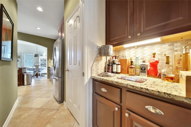 17003 Buffalo Peak Ct, Humble, TX 77346 - indoor dry bar featuring freestanding refrigerator, backsplash, light tile patterned flooring, arched walkways, and recessed lighting