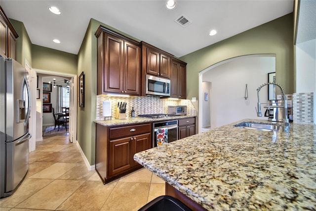 17003 Buffalo Peak Ct, Humble, TX 77346 - kitchen with stainless steel appliances, arched walkways, backsplash, light stone countertops, and recessed lighting
