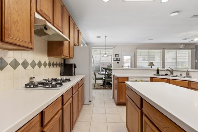 10415 Claybrook Dr, Houston, TX 77089 - kitchen featuring under cabinet range hood, white gas cooktop, brown cabinetry, backsplash, and light countertops