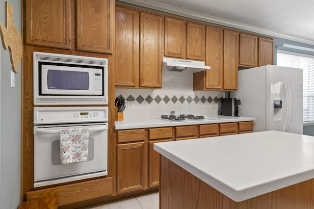 10415 Claybrook Dr, Houston, TX 77089 - kitchen with white appliances, under cabinet range hood, brown cabinets, tasteful backsplash, and a kitchen island