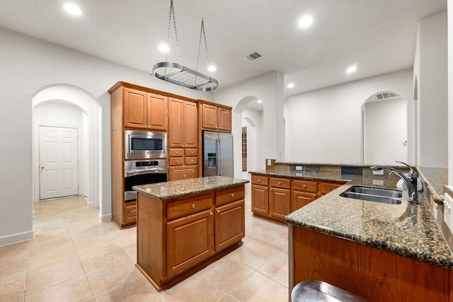 21510 Briar Landing Ln, Katy, TX 77450 - kitchen with appliances with stainless steel finishes, arched walkways, dark stone countertops, brown cabinetry, and recessed lighting